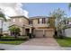 Two-story house with tan siding, three-car garage, and landscaped yard at 9036 Arbors Edge Trl, Windermere, FL 34786
