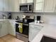 Well-equipped kitchen with stainless steel appliances, light green cabinetry, and white countertops at 148 Brunello Dr, Davenport, FL 33897