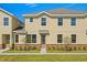 Two-story tan house with stone accents and landscaping at 141 Holly Village Dr, Davenport, FL 33837