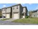 Tan two-story townhome with a two-car garage and a small front yard at 470 Lake Shore Pkwy, Davenport, FL 33896
