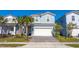 Two-story house with light blue siding, white garage door, and palm trees at 7400 Oakmoss Loop, Davenport, FL 33837