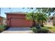 Orange house exterior with a two-car garage and palm trees at 836 Grand Canal Dr, Kissimmee, FL 34759