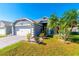 Gray house with white garage door, landscaping, and palm trees at 10035 Marguex Dr, Orlando, FL 32825