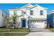 Two-story house with a blue door, white exterior, and a three-car garage at 1540 Maidstone Ct, Davenport, FL 33896