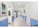 Bright hallway with light tile floors and blue accent walls, offering views into living and bathroom areas at 1540 Maidstone Ct, Davenport, FL 33896
