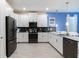 Modern kitchen with white cabinets, dark appliances, and a large island at 1540 Maidstone Ct, Davenport, FL 33896