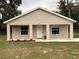 Tan house with white door, covered porch, and landscaping at 9650 Nw Gainesville Rd, Ocala, FL 34475