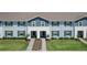 Two-story townhomes with light blue and gray siding, paved walkways, and green lawns at 617 Jasmine Ln, Davenport, FL 33897