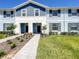 Two-story townhome with light blue and gray siding, a paved walkway, and a well-manicured lawn at 617 Jasmine Ln, Davenport, FL 33897