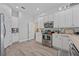 Modern kitchen with white cabinets, stainless steel appliances, and wood-look flooring at 6807 Sylvan Woods Dr, Sanford, FL 32771