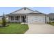 Gray house with white garage door, landscaping, and a concrete driveway at 4694 Monica St, The Villages, FL 32163