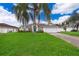 Single-story house with a green lawn, driveway, and palm trees at 577 Sunridge Woods Blvd, Davenport, FL 33837