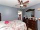 Bedroom with floral bedding, dresser and ceiling fan at 552 Eagle Ct, Poinciana, FL 34759