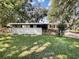 House exterior showcasing a white brick facade, fenced yard, and mature trees at 3700 Timber Trl, Orlando, FL 32808