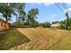 Large, mostly unkempt backyard with some trees and a fence at 6427 Sunshine St, Orlando, FL 32818