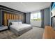 Modern bedroom with gray upholstered bed, wood wall accent, and large window at 836 Desert Mountain Ct, Reunion, FL 34747