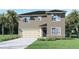 Two-story house with light brown exterior, neutral colored garage door, and landscaping at 2842 Moulin Rd, Davenport, FL 33837