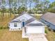 Gray house with white garage door and blue front door, landscaping, and driveway at 308 Halstead Dr, Davenport, FL 33897