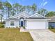 Gray house with white garage door and blue front door, landscaping, and driveway at 308 Halstead Dr, Davenport, FL 33897