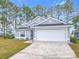 Gray house with white garage door and blue front door, landscaping, and driveway at 308 Halstead Dr, Davenport, FL 33897