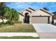 Tan one-story house with a two-car garage and palm trees at 7922 Elmstone Cir, Orlando, FL 32822