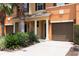 Townhouse exterior with attached garage, landscaping, and palm trees at 875 Assembly Ct, Reunion, FL 34747
