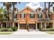 Front view of two story townhouses with attached garages, lush landscaping, and palm trees at 875 Assembly Ct, Reunion, FL 34747