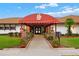 View of the Somerset Club's entrance, with a red awning and landscaping at 11533 Sandy Hill Dr, Orlando, FL 32821