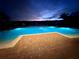 Inviting community pool at night, surrounded by lounge chairs and palm trees at 6430 S Goldenrod Rd # 15B, Orlando, FL 32822