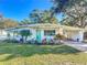 Cute white house with teal front door, carport and nicely manicured lawn at 121 Ellison Ave, New Smyrna Beach, FL 32168