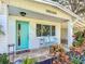 Inviting front porch with teal door and vintage metal chairs at 121 Ellison Ave, New Smyrna Beach, FL 32168