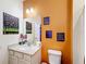 Bright bathroom with a white vanity and toilet, featuring unique wall art at 2477 Shanti Dr, Kissimmee, FL 34746