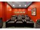 Home theater with black reclining seats and red walls at 7423 Sparkling Ct, Reunion, FL 34747