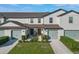 Two-story townhouse with light-colored siding and green garage doors at 1592 Wynford Cir, Tavares, FL 32778