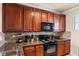 View of kitchen with granite countertops and dark wood cabinets at 903 Charo Pkwy # 836, Davenport, FL 33897