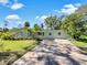 Light blue house with a brick driveway, landscaping, and lush green lawn at 2410 Sanford Ave, Sanford, FL 32771