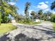Cute light green house with a long gravel driveway and lush landscaping at 2410 Sanford Ave, Sanford, FL 32771
