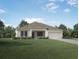 Single-story home with light beige exterior, dark gray roof, and landscaped lawn at 2636 Brookline Ave, New Smyrna Beach, FL 32168