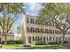 Tan three-story townhome with black shutters and lush landscaping at 1054 Waterside Dr, Celebration, FL 34747