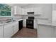 Modern kitchen with white cabinets, black appliances, and granite countertops at 77 Pine Radl, Ocala, FL 34472