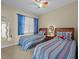 Two twin beds in a bright bedroom with blue striped bedding and a ceiling fan at 8336 Riverdale Ln, Davenport, FL 33896