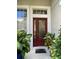 Front entrance with a red door and glass panels, flanked by lush greenery at 912 Hire Cir, Ocoee, FL 34761
