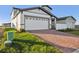 Two-story house with gray and white siding, a white garage door, and a brick driveway at 140 Archer Ave, Lake Alfred, FL 33850