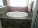 Oval garden bathtub with dark tile surround and window at 236 Barrington Dr, Haines City, FL 33844