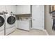 Bright laundry room with white cabinets, washer, dryer, and utility sink at 932 Tassleflower Trl, Saint Cloud, FL 34771