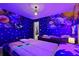Themed bedroom with twin beds, space decor, and vibrant lighting at 4428 Kaipo Rd, Davenport, FL 33897