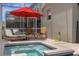 Private screened-in spa with lounge chairs and red umbrella at 8940 Play Through Dr, Davenport, FL 33896