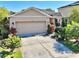 Tan one-story house with a two-car garage, landscaping, and a driveway at 1936 Marabou Dr, Davenport, FL 33896