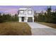 Two-story house with gray metal roof and gray garage door, sits on a grassy lot at 765 6Th Ave, Osteen, FL 32764