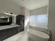 Luxurious bathroom with soaking tub, marble tile, and dark cabinetry at 547 Sanctuary Golf Pl, Apopka, FL 32712